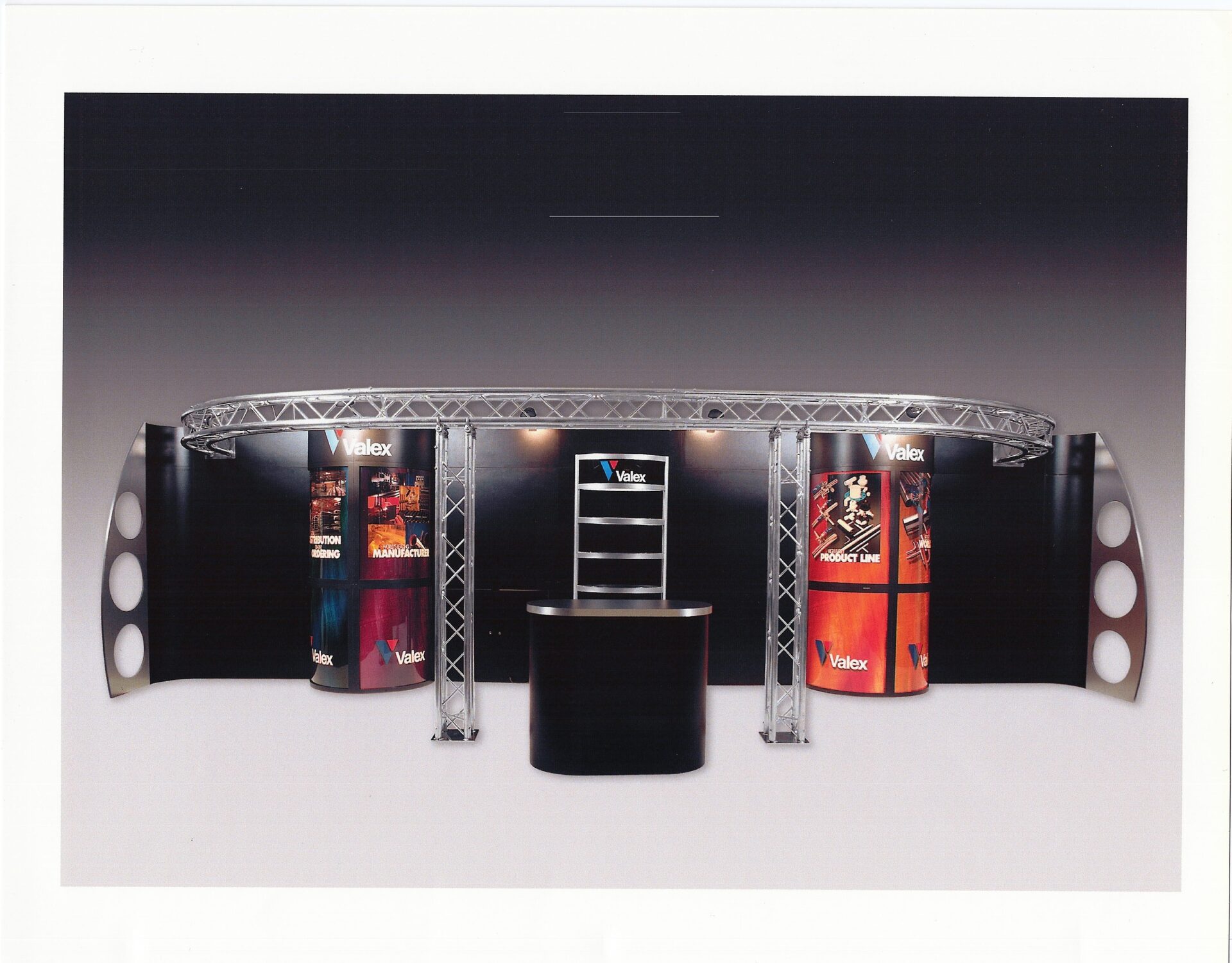 A trade show exhibit with a curved frame structure and large promotional graphics displayed on the walls. The center features a counter with shelving behind it, and "Valex" logos are visible on multiple panels. The setup is well-lit, creating a sleek and professional look.